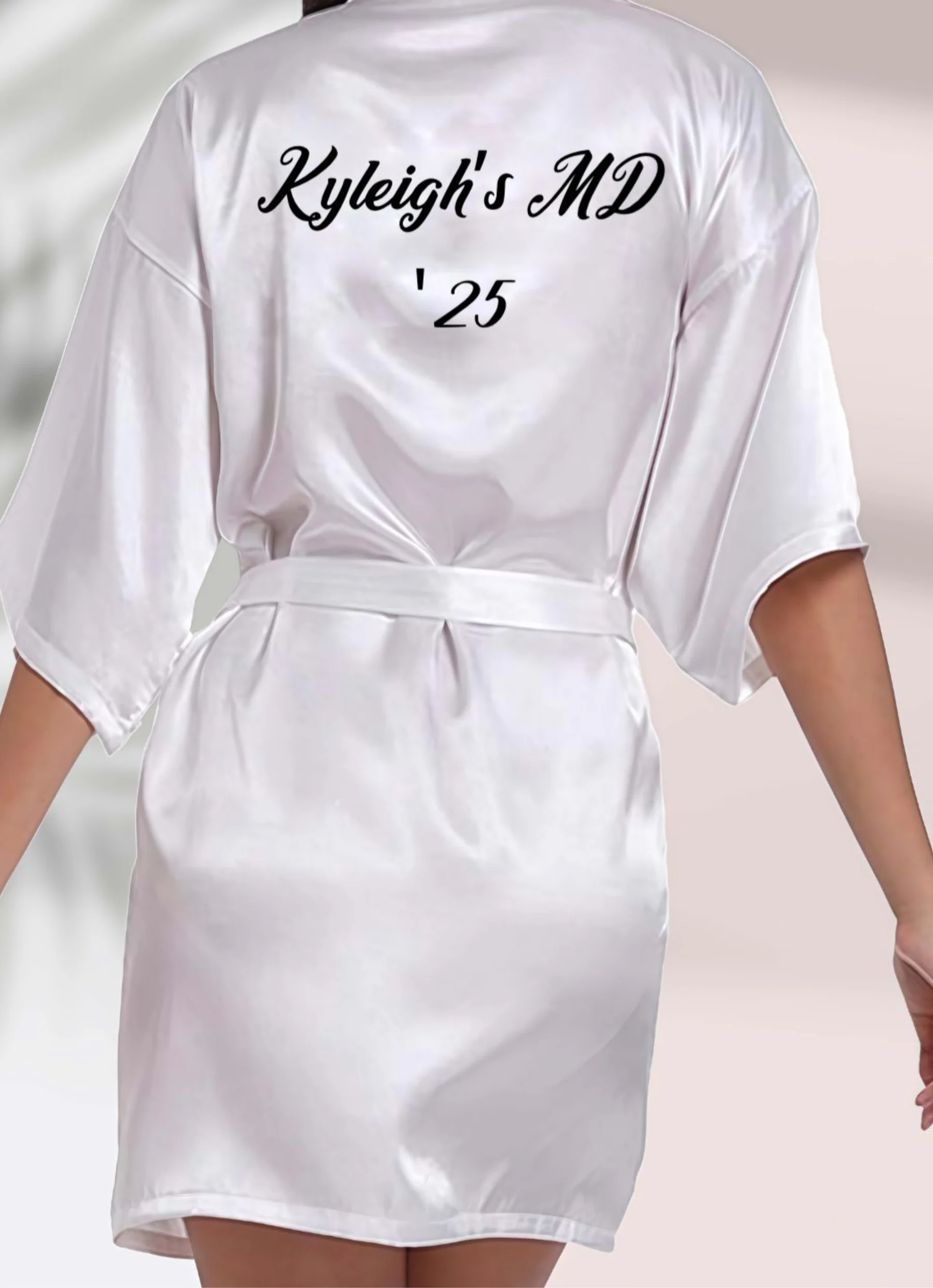White satin robe printed on the back with the name Kyleigh and the year 25