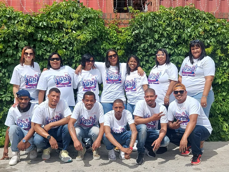 Fifteen colleagues outdoors in matching white printed reunion t-shirts